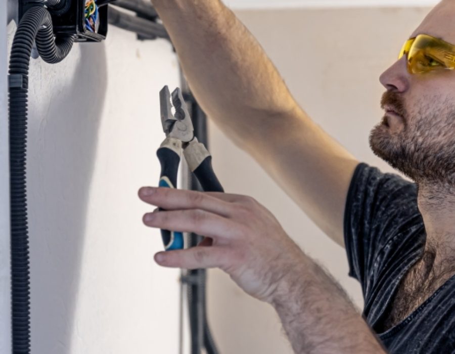 An electrician is mounting electric sockets on the white wall indoors.